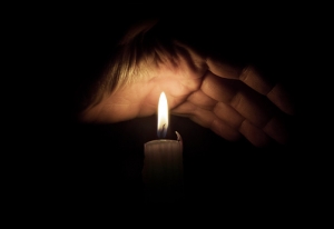Open hand over candle light. On dark background.